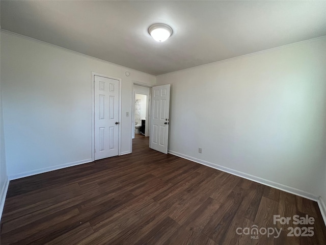 unfurnished bedroom with dark wood-type flooring, ornamental molding, and baseboards