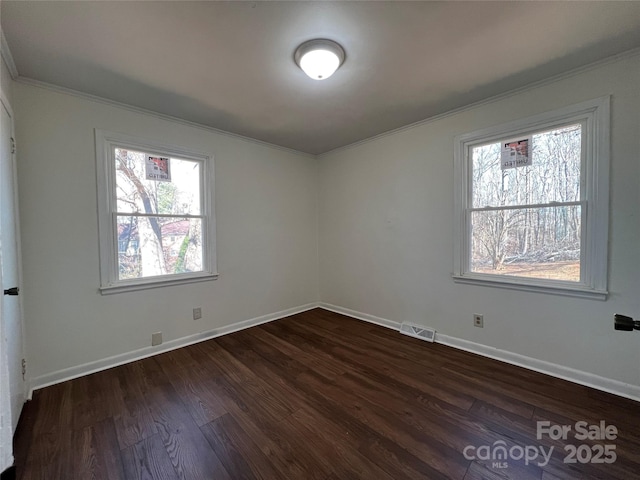 unfurnished room featuring baseboards, visible vents, dark wood-style flooring, and ornamental molding