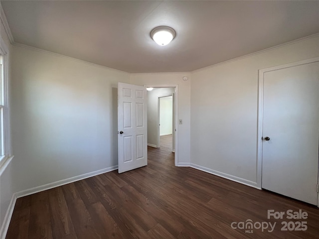 unfurnished bedroom featuring crown molding, baseboards, and dark wood-style flooring