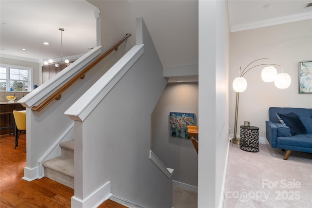 staircase featuring hardwood / wood-style flooring, an inviting chandelier, and ornamental molding