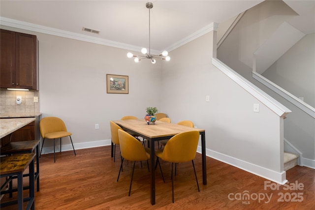 dining space featuring dark hardwood / wood-style flooring, ornamental molding, and an inviting chandelier