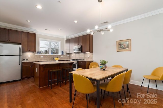 dining area featuring dark hardwood / wood-style flooring, an inviting chandelier, and crown molding