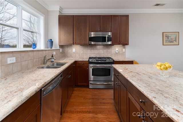 kitchen featuring appliances with stainless steel finishes, tasteful backsplash, light stone counters, and sink