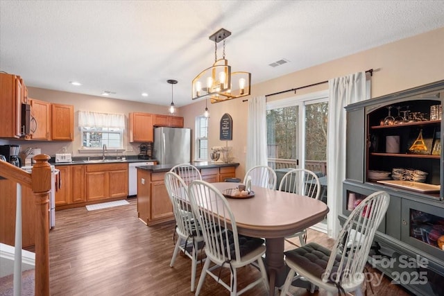 dining area featuring a textured ceiling, dark wood-type flooring, sink, and an inviting chandelier