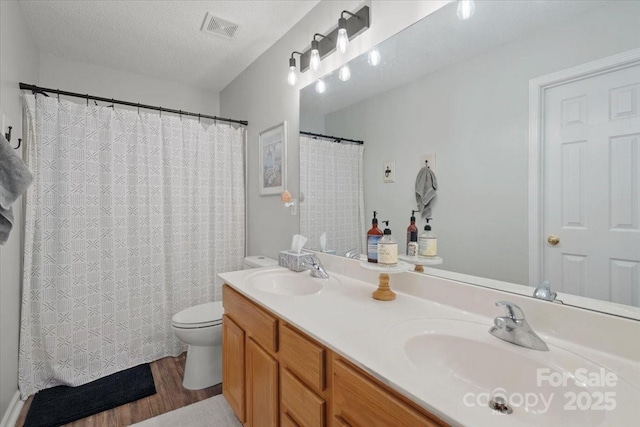 bathroom with vanity, hardwood / wood-style floors, a textured ceiling, and toilet