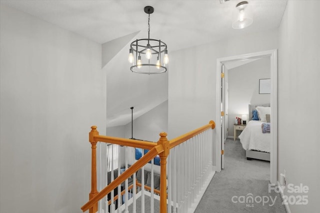 corridor featuring light colored carpet, lofted ceiling, and a notable chandelier