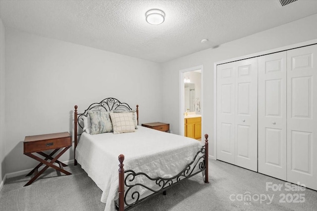 carpeted bedroom with ensuite bathroom, a closet, and a textured ceiling