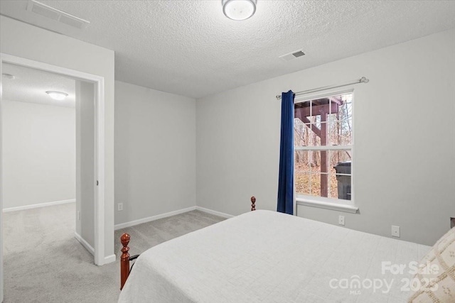 bedroom with light colored carpet and a textured ceiling