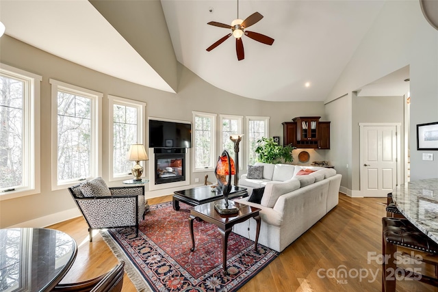 living room with light hardwood / wood-style floors, high vaulted ceiling, and ceiling fan