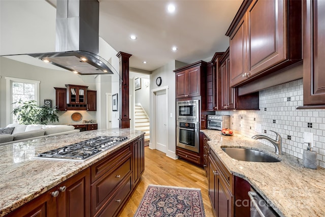 kitchen featuring light stone countertops, appliances with stainless steel finishes, ventilation hood, sink, and light hardwood / wood-style floors