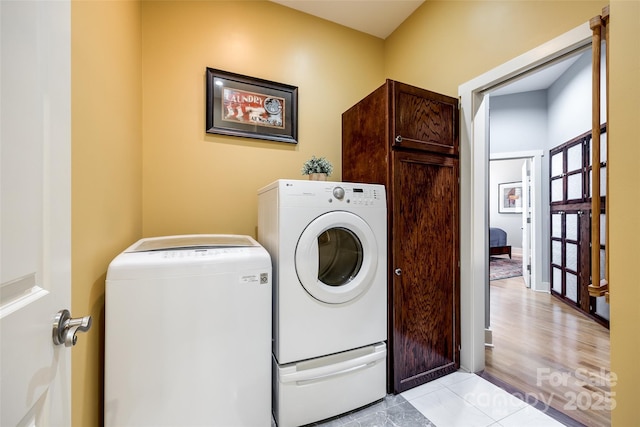 laundry area with independent washer and dryer and light tile patterned flooring