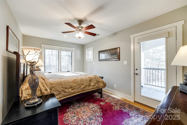 bedroom featuring access to exterior, wood-type flooring, multiple windows, and ceiling fan