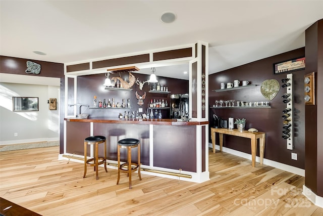 bar featuring light wood-type flooring and hanging light fixtures