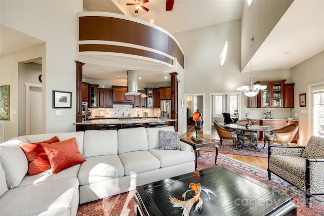 living room with ceiling fan with notable chandelier and a high ceiling