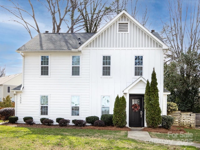 view of front of home featuring a shingled roof, board and batten siding, and a front yard