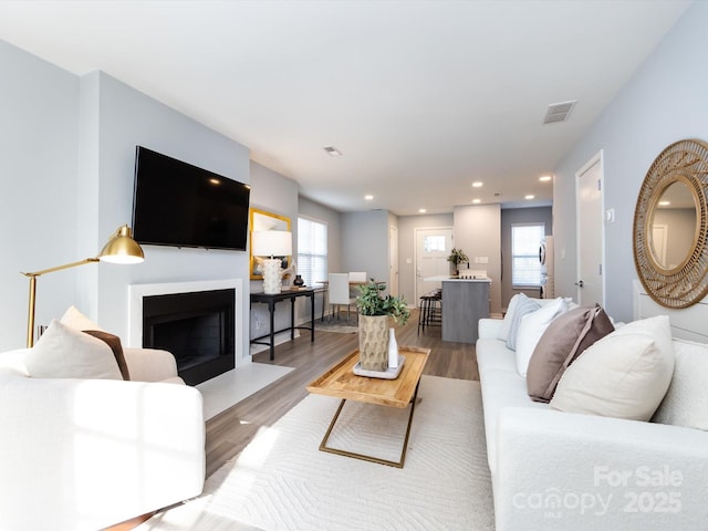 living area with a fireplace with flush hearth, wood finished floors, and recessed lighting