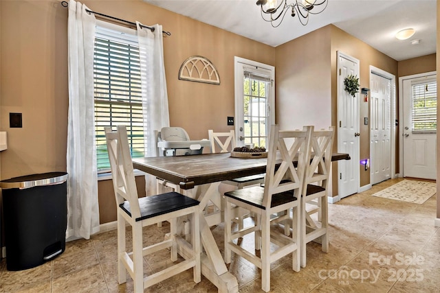 dining area featuring light tile patterned flooring, a healthy amount of sunlight, and a notable chandelier