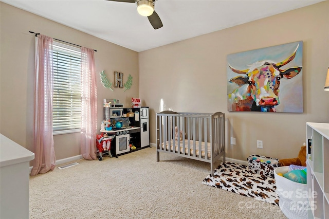 bedroom featuring carpet flooring, a nursery area, and ceiling fan