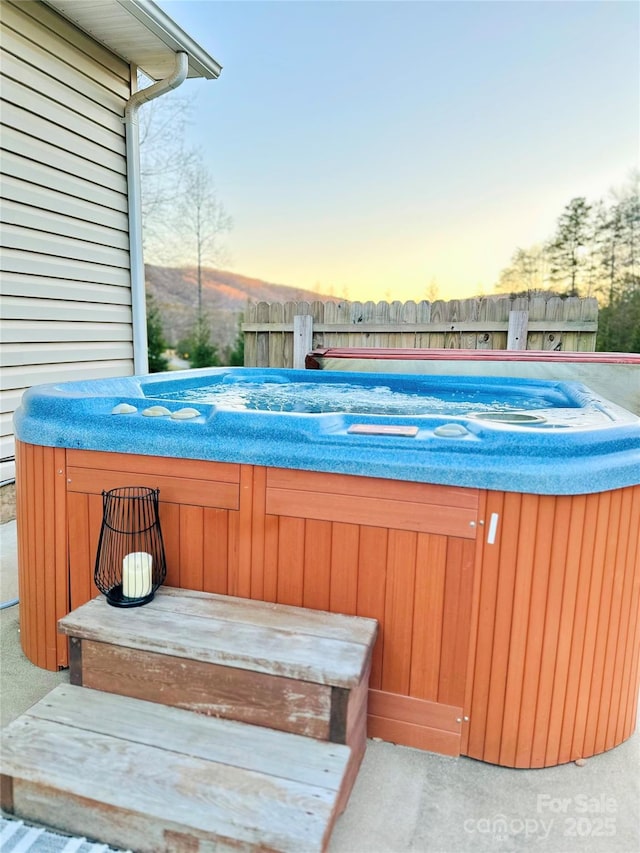 pool at dusk with a hot tub