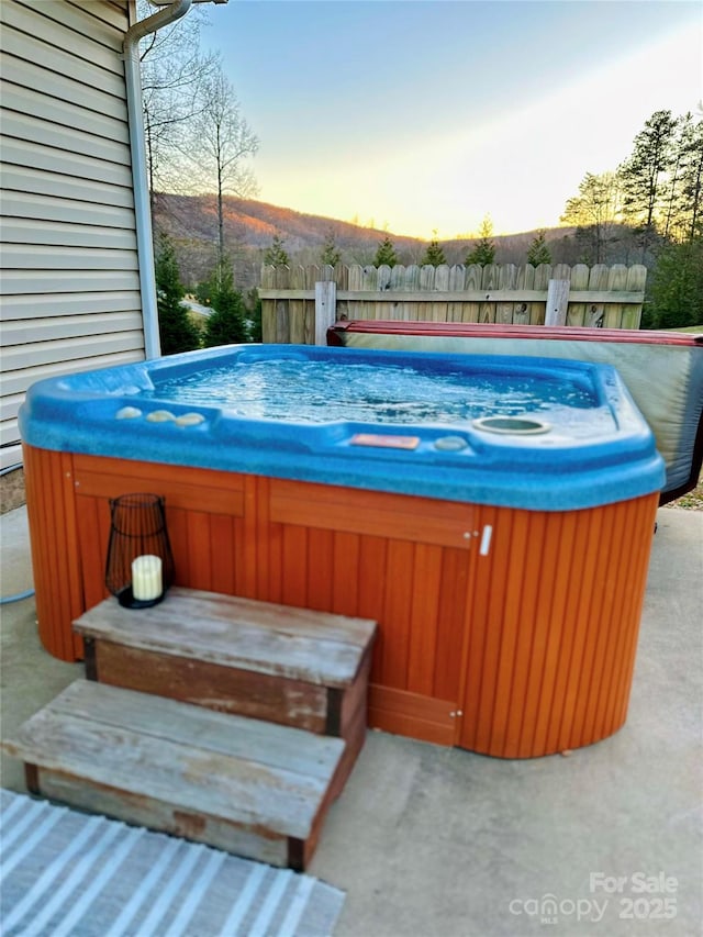 pool at dusk featuring a hot tub