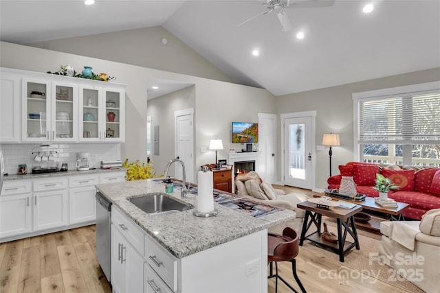 kitchen featuring light stone countertops, white cabinets, an island with sink, decorative backsplash, and sink