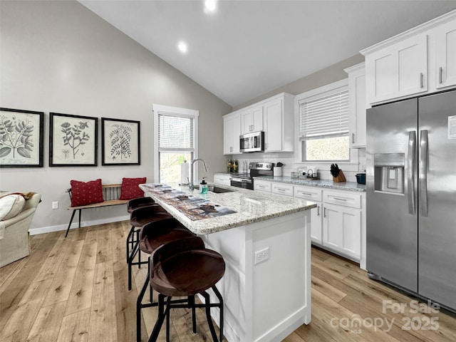 kitchen featuring appliances with stainless steel finishes, white cabinets, a kitchen island, and sink