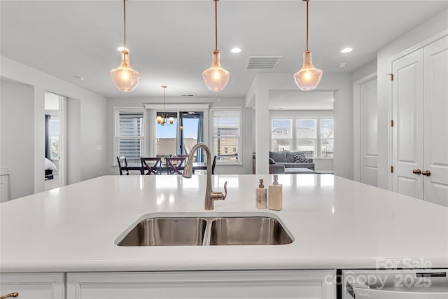 kitchen with sink, white cabinetry, hanging light fixtures, and dishwashing machine