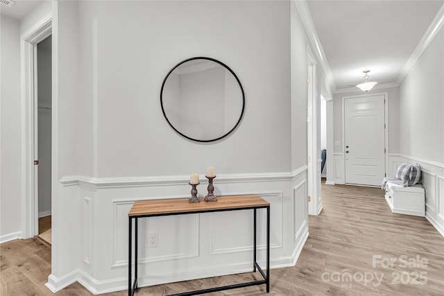 hallway with light hardwood / wood-style floors and ornamental molding