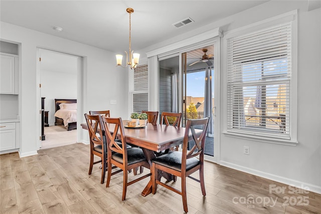 dining space with ceiling fan with notable chandelier and light hardwood / wood-style floors