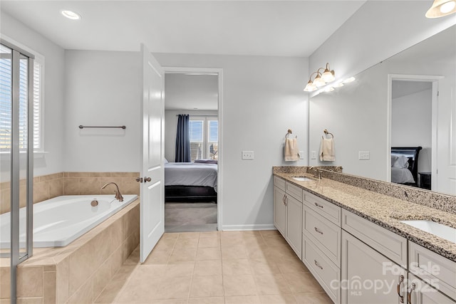 bathroom featuring tile patterned flooring, vanity, and tiled bath