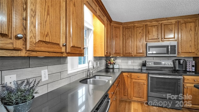 kitchen with a textured ceiling, decorative backsplash, sink, and stainless steel appliances