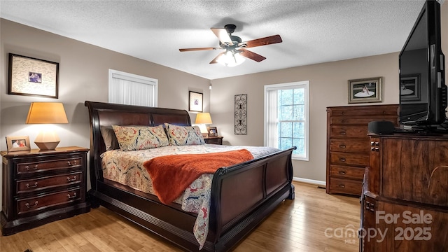 bedroom featuring ceiling fan, light hardwood / wood-style flooring, and a textured ceiling