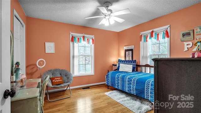 bedroom with hardwood / wood-style floors, a textured ceiling, and ceiling fan