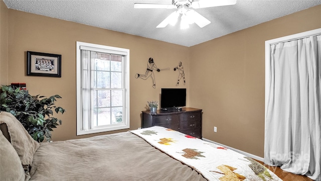 bedroom with multiple windows, ceiling fan, a textured ceiling, and hardwood / wood-style flooring