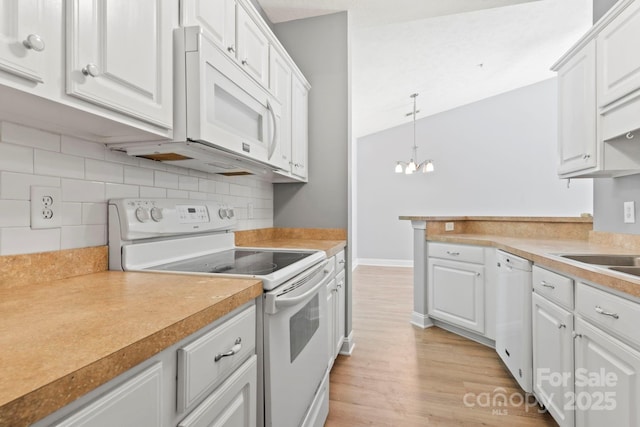 kitchen featuring white cabinets, decorative light fixtures, and white appliances