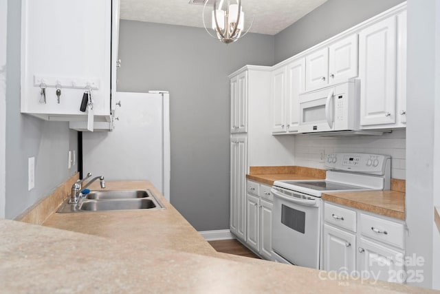 kitchen with white cabinetry, sink, hanging light fixtures, backsplash, and white appliances