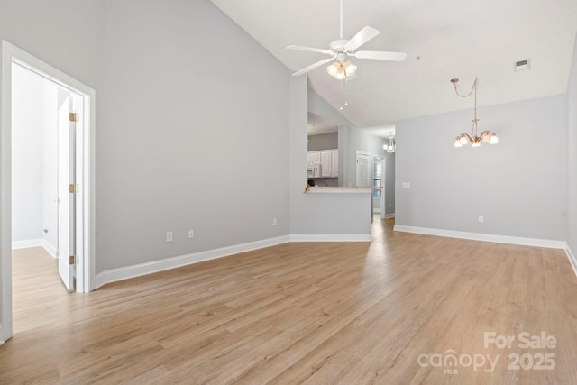 unfurnished living room with ceiling fan with notable chandelier, light hardwood / wood-style floors, and high vaulted ceiling