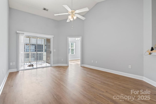 empty room featuring wood-type flooring, high vaulted ceiling, and ceiling fan