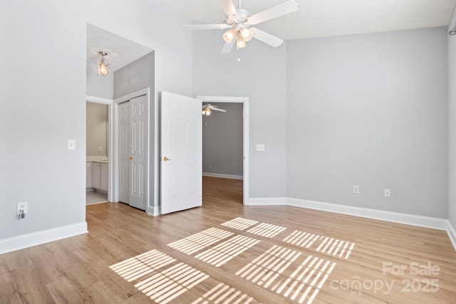 interior space featuring high vaulted ceiling, ceiling fan with notable chandelier, and light wood-type flooring