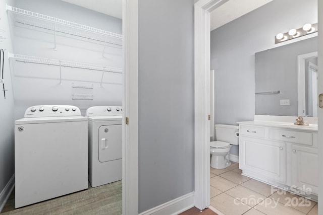 laundry room with light tile patterned floors, sink, and washing machine and clothes dryer