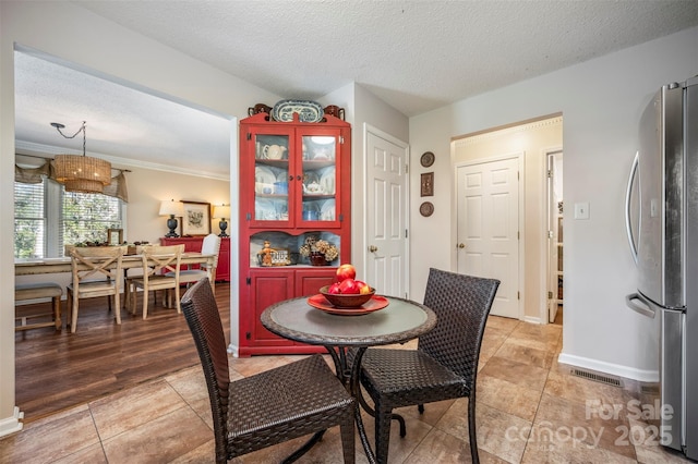 tiled dining room featuring crown molding and a textured ceiling