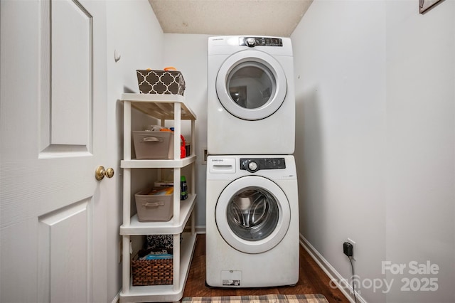 washroom with a textured ceiling, dark hardwood / wood-style floors, and stacked washer and clothes dryer