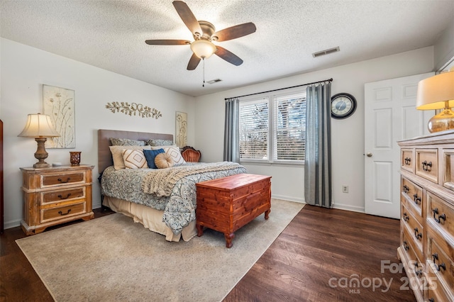 bedroom with a textured ceiling, ceiling fan, and dark wood-type flooring