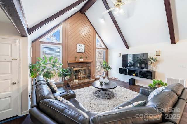 living room with dark hardwood / wood-style flooring, wood walls, vaulted ceiling with beams, and a fireplace