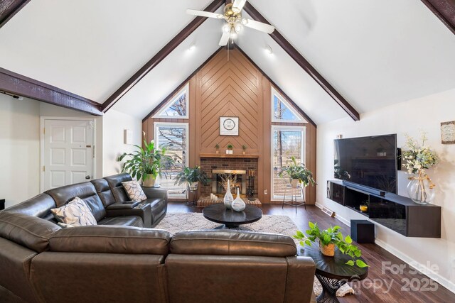 living room featuring a brick fireplace, lofted ceiling with beams, ceiling fan, and dark wood-type flooring