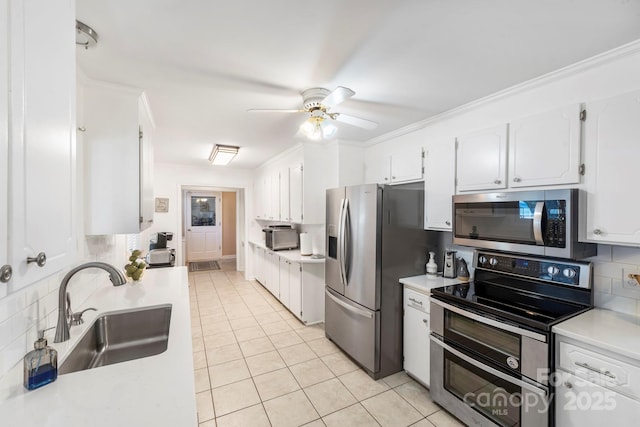 kitchen featuring light tile patterned floors, tasteful backsplash, white cabinetry, appliances with stainless steel finishes, and sink