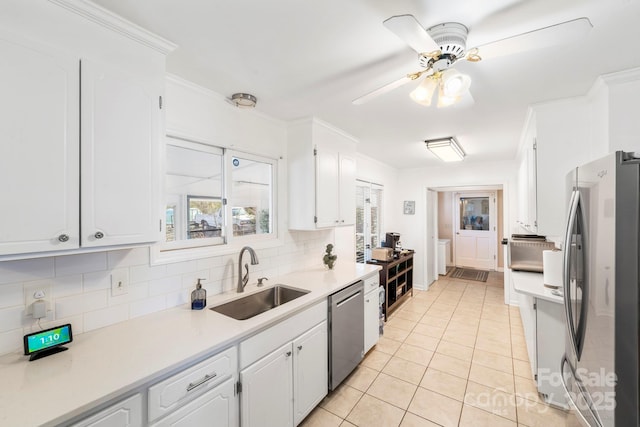 kitchen with stainless steel appliances, ceiling fan, white cabinetry, light tile patterned flooring, and sink