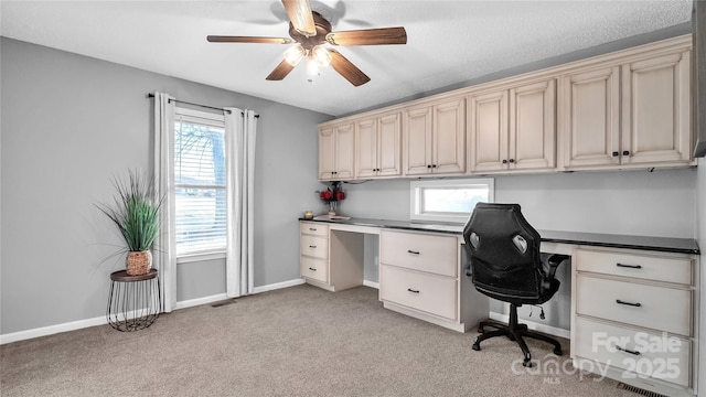 home office with ceiling fan, light colored carpet, built in desk, and a textured ceiling