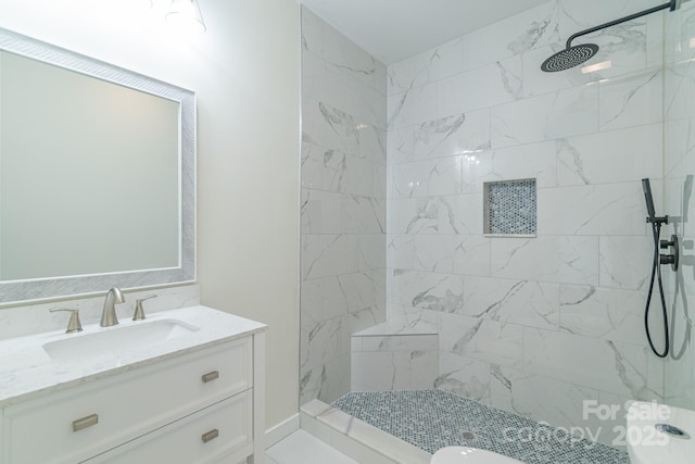 bathroom with a tile shower and vanity