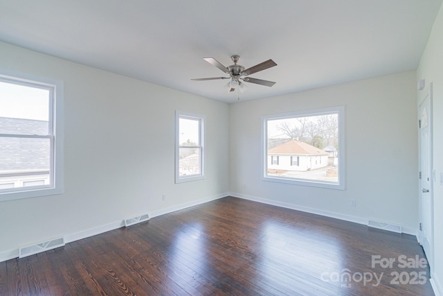 empty room featuring a wealth of natural light, dark wood-type flooring, and ceiling fan